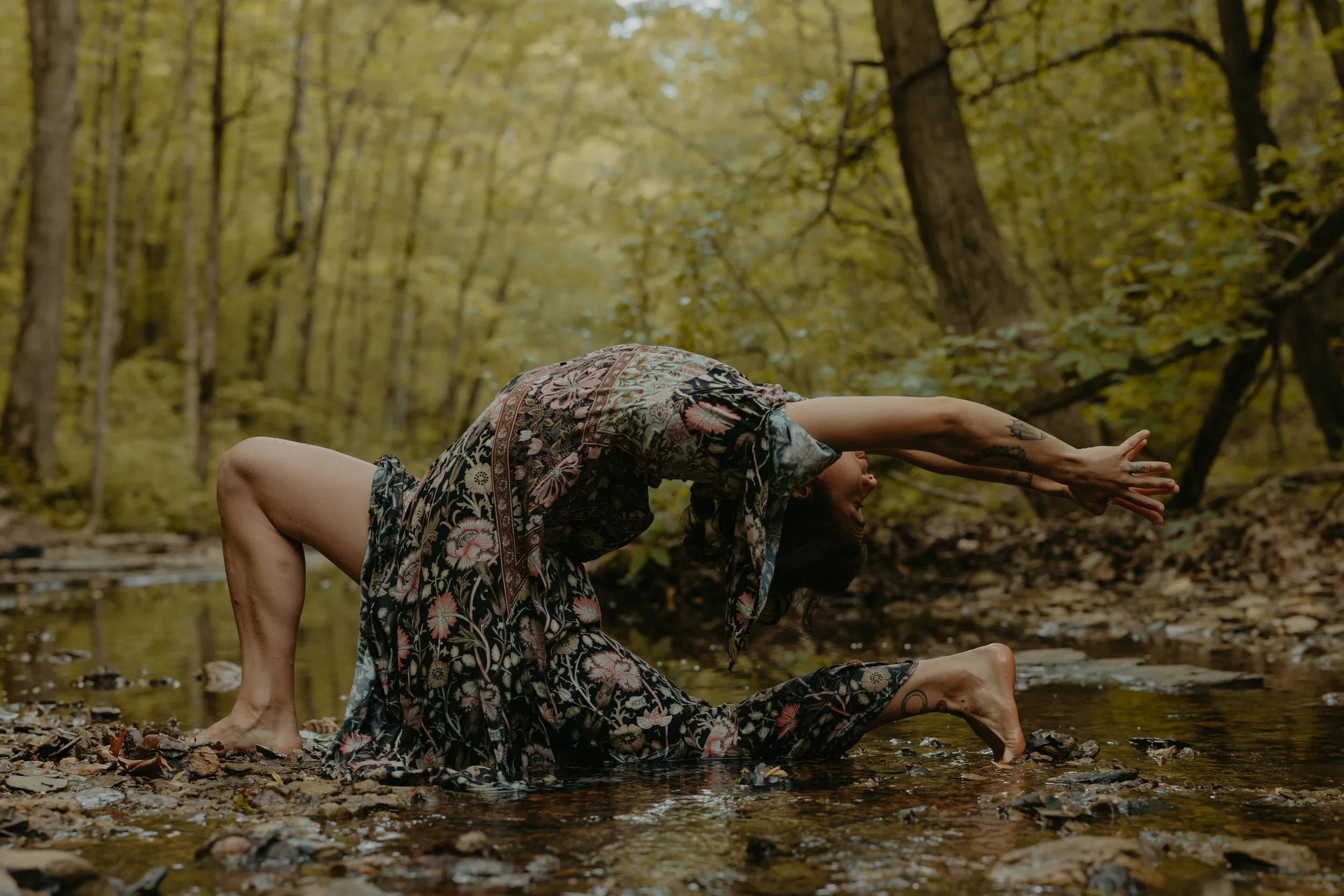 Woman in a floral dress doing a back bend in a river