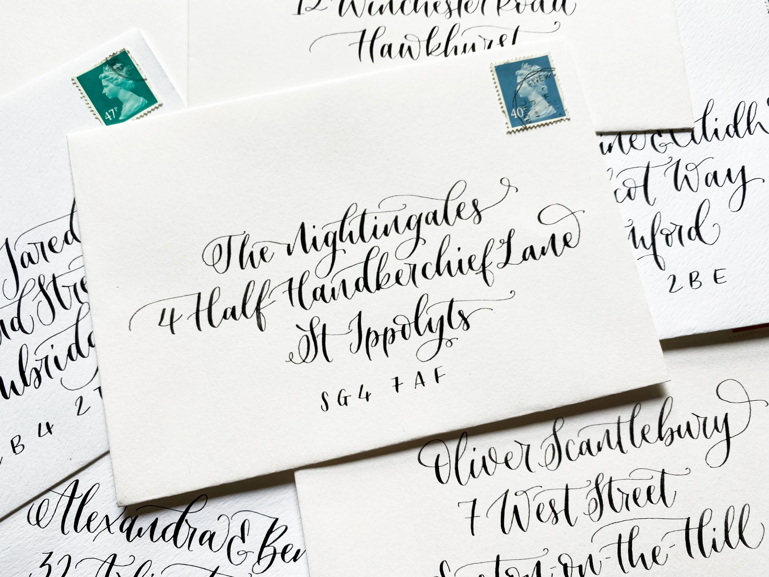 A pile of envelopes featuring modern calligraphy in a whimsical style