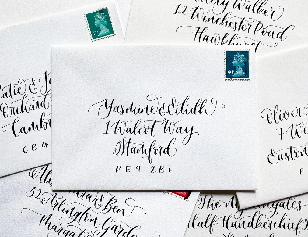 A pile of calligraphy envelopes with addresses in a modern black script