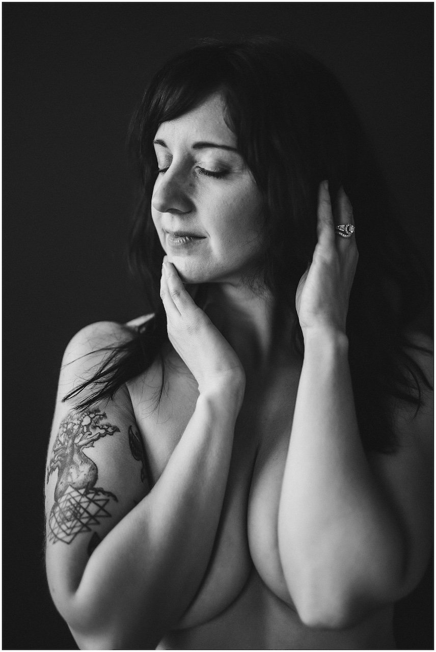 A girl covering her chest with arms against a black backdrop in a Cleveland photo studio. 