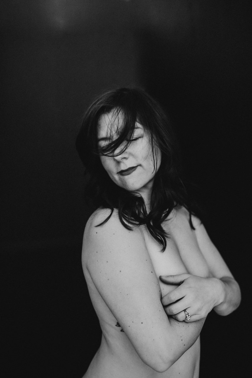 A woman in black hair posing for a tastefully nude photograph for a boudoir photograph. 