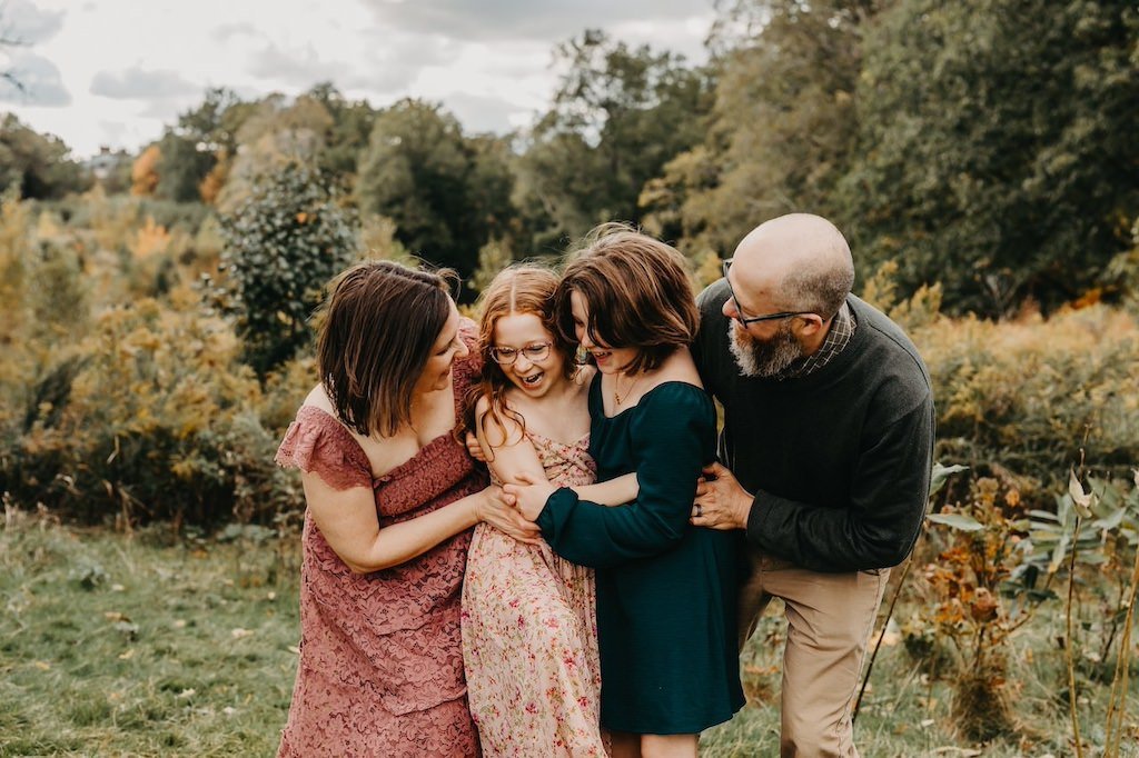 A family with two girls in Acacia Reservation posing for fall photos. 