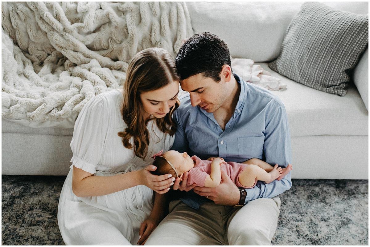 Parents of baby girl sitting on floor of living room in Bay Village during photography.