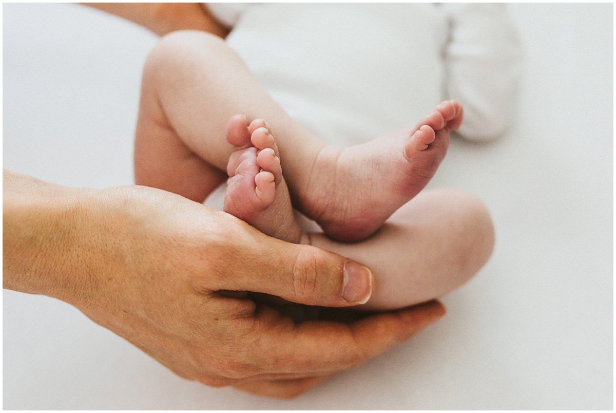 Newborn feet in dad's hands posing for in home photo session. 