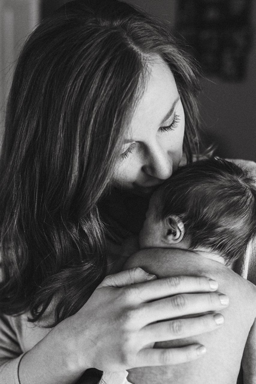 Mom kissing skin of newborn during a in-home lifestyle photography. 