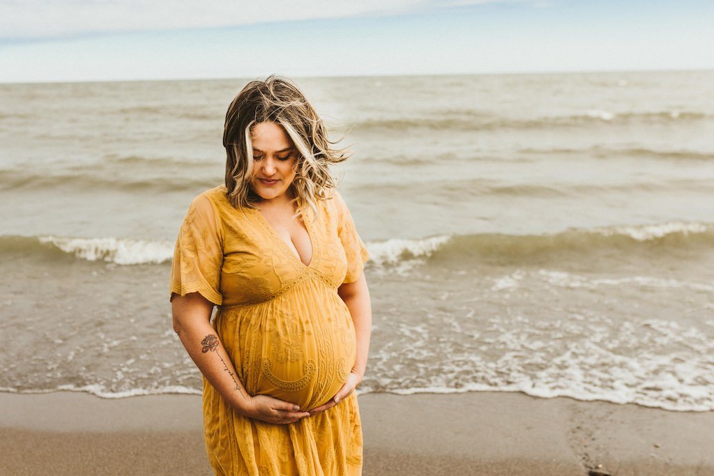 Huntington Beach maternity session with woman wearing yellow long dress. 