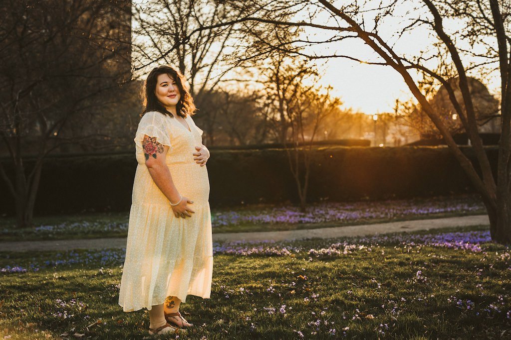 Pregnant woman wearing a yellow dress in the spring at the Cleveland Museum of Art during photo shoot. 