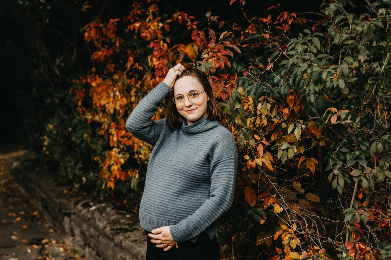 A pregnant woman posing behind fall colors in Shaker Hts, Ohio.