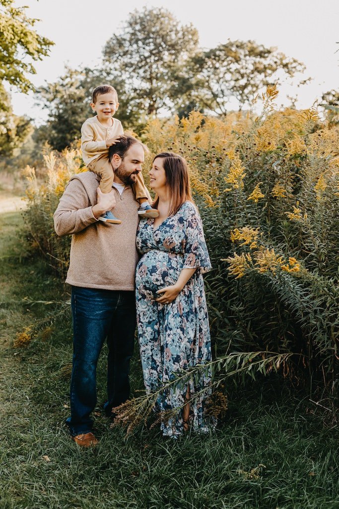 Family of three expecting baby brother posing for maternity pictures in Cleveland, OH park. 