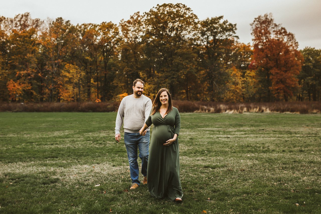 Fall maternity session of parents to be holding hands in Rocky River park near Cleveland, Ohio.