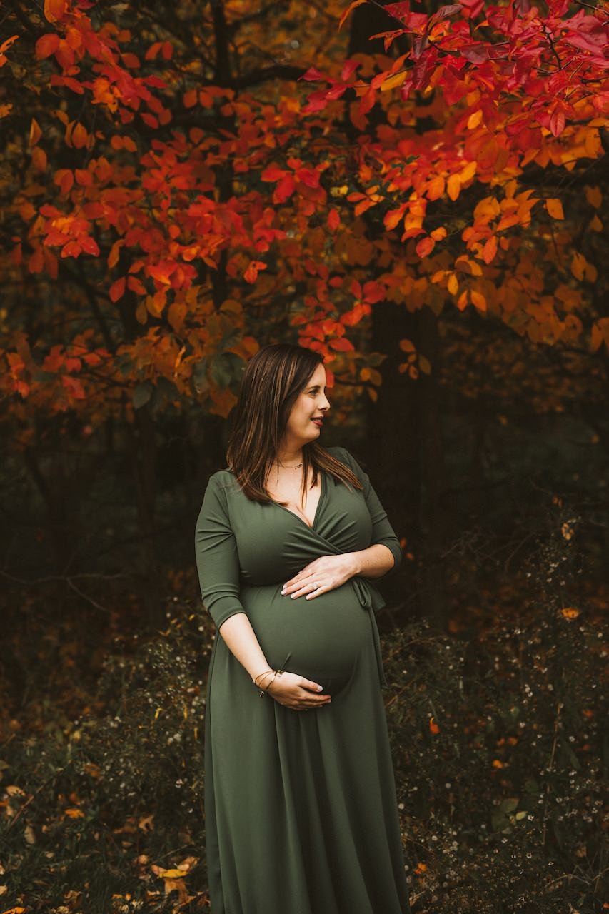 Fall maternity portrait of pregnant woman wearing green gown in Rocky River Park, Ohio. 