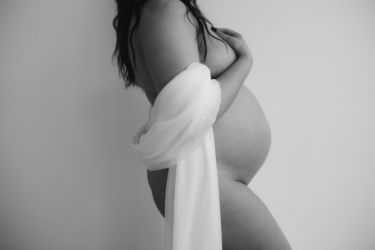 Black and white maternity photo of pregnant woman wearing white fabric drape in Cleveland, Ohio.