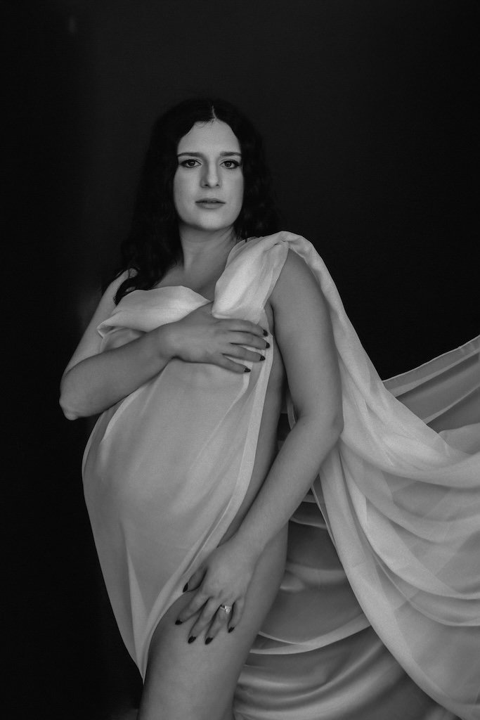 Artistic black and white photograph of pregnant woman covered with white fabric in Cleveland, OH studio.