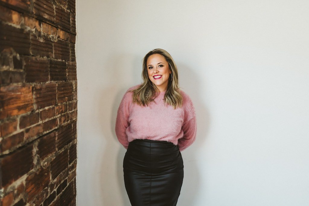 Business woman dressed in leather skirt and pink sweater posing for headshot during a branding session. 
