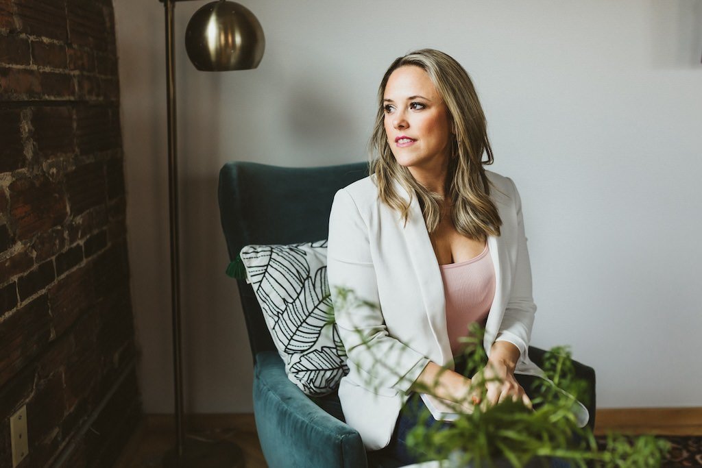 Personal branding shoot of woman sitting in blue lounge chair in home setting of Cleveland, Ohio. 