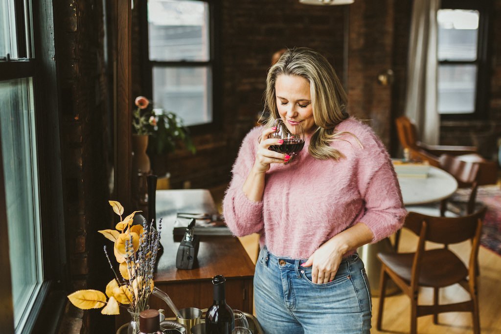Personal branding shoot of woman having a glass of wine while posing for a photograph.