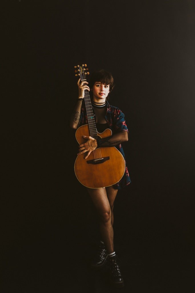 Personal branding shoot of young musical artist and guitar in photography studio. 