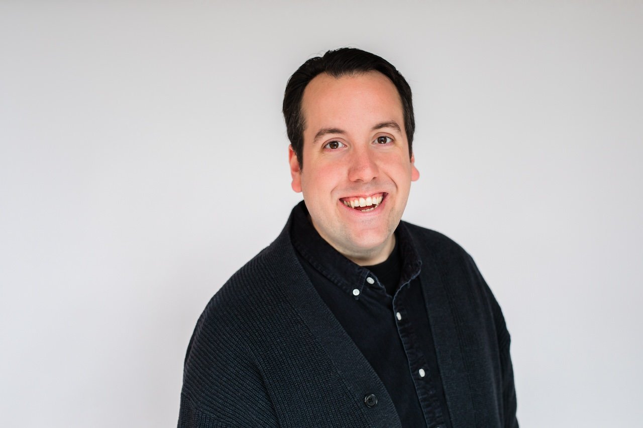 Professional headshot of man in black sweater against white backdrop in Cleveland, Ohio studio. 