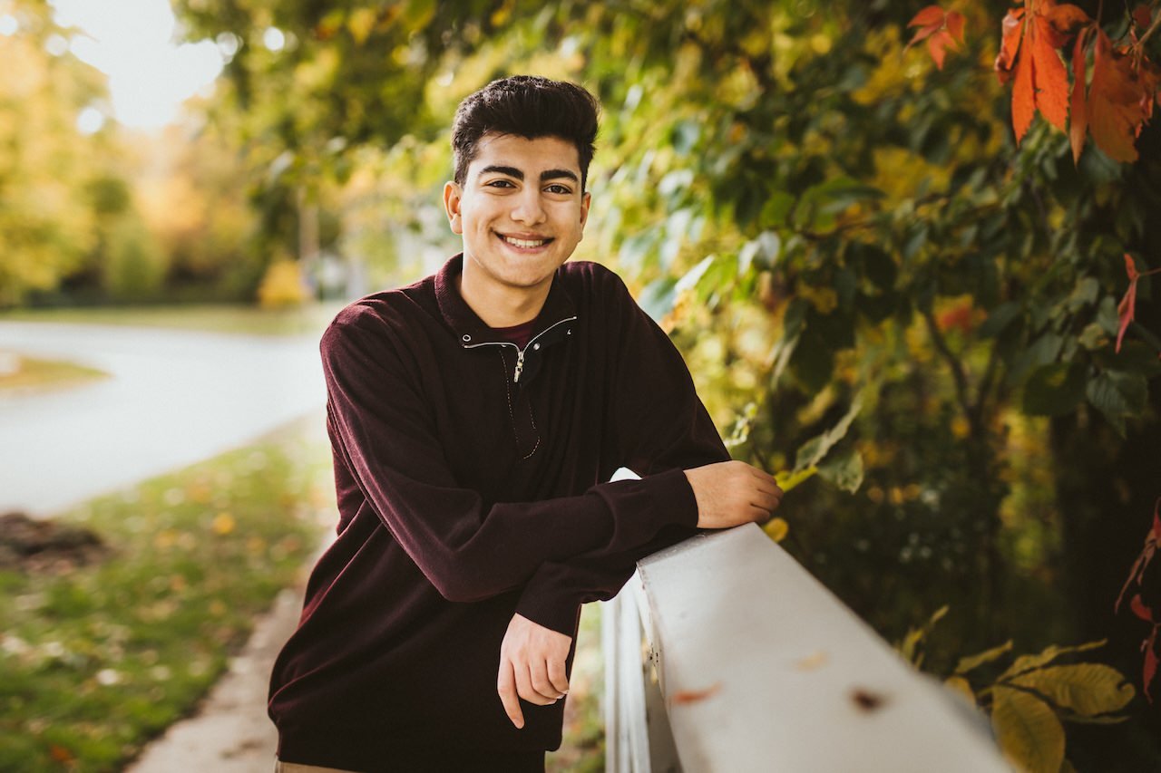 A high school senior boy posing for pictures in fall setting in Shaker Heights. 