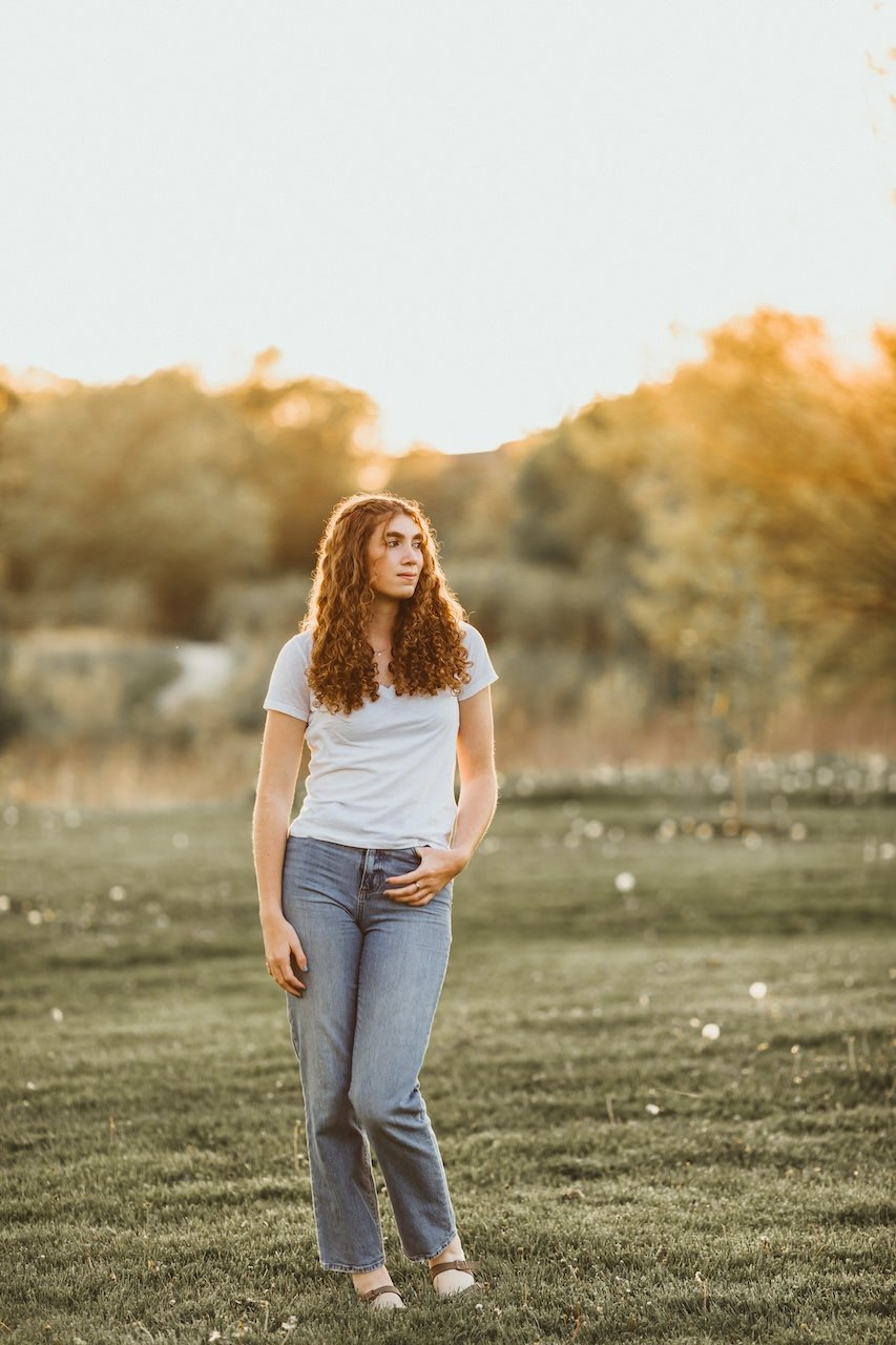 Tall girl with long curly hair posing for senior picture during golden hour in Acacia Reservation. 