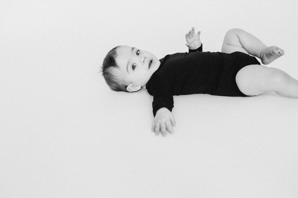 A baby girl laying on white photograph backdrop in Cleveland photo studio.