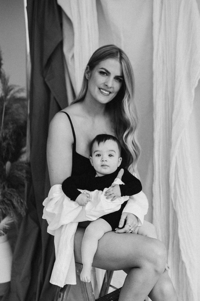 A portrait of mother holding baby girl in studio photography setting with mom wearing a bodysuit. 