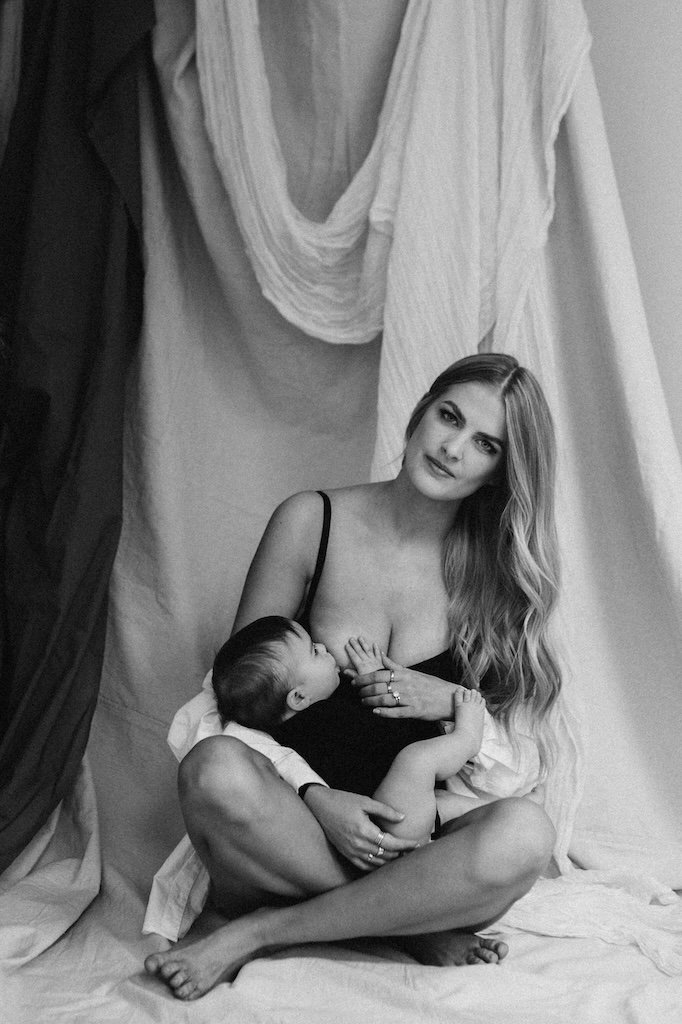 Mom wearing a black bodysuit breastfeeding baby during a portrait session in Cleveland photo studio.