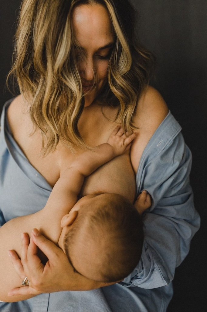 A mom nursing her baby son in button down shirt for a portrait in a studio setting. 