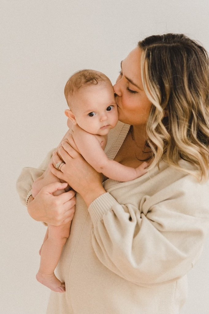 Mom kissing baby son while being photographed in a Cleveland studio. 