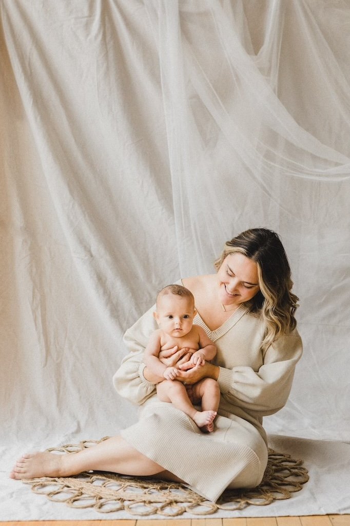 A natural and raw photo with mom and baby in-front of canvas backdrop. 