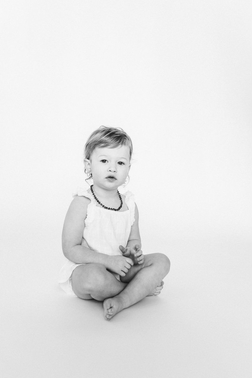 A toddler girl posing for black and white portrait in modern Cleveland studio.
