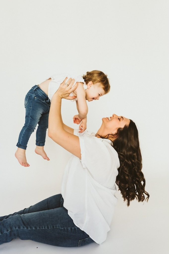 A mom holding toddler girl high up in her arm during photo shoot in Cleveland. 