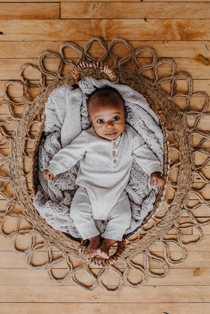 A baby boy laying in a basket smiling at photographer in the cleveland studio. 