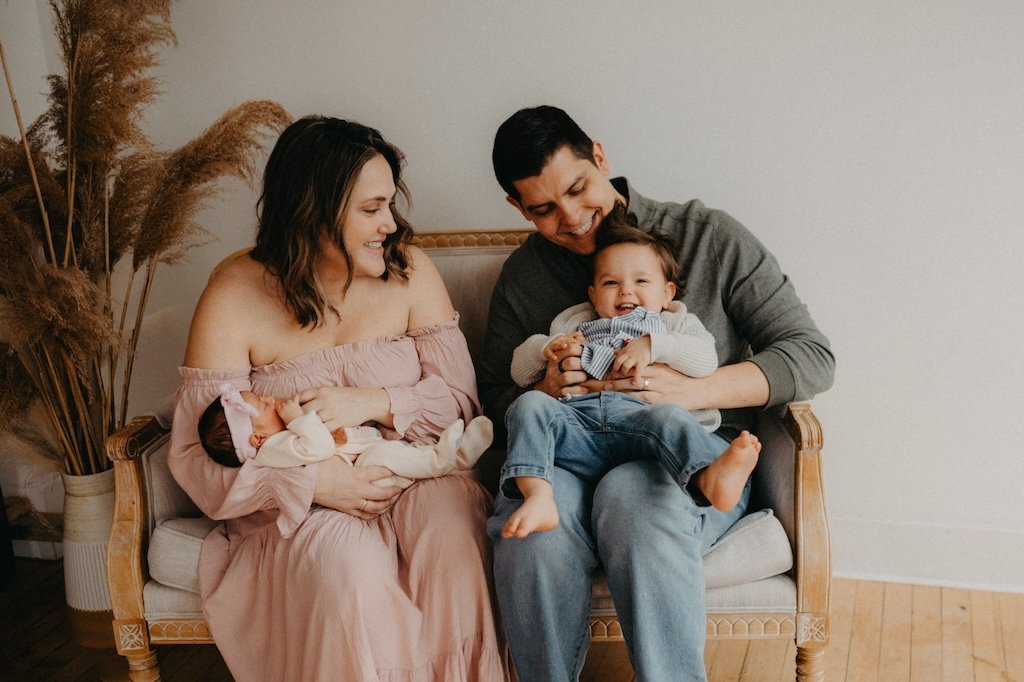 Family of four sitting on sofa in photo studio in Cleveland. 