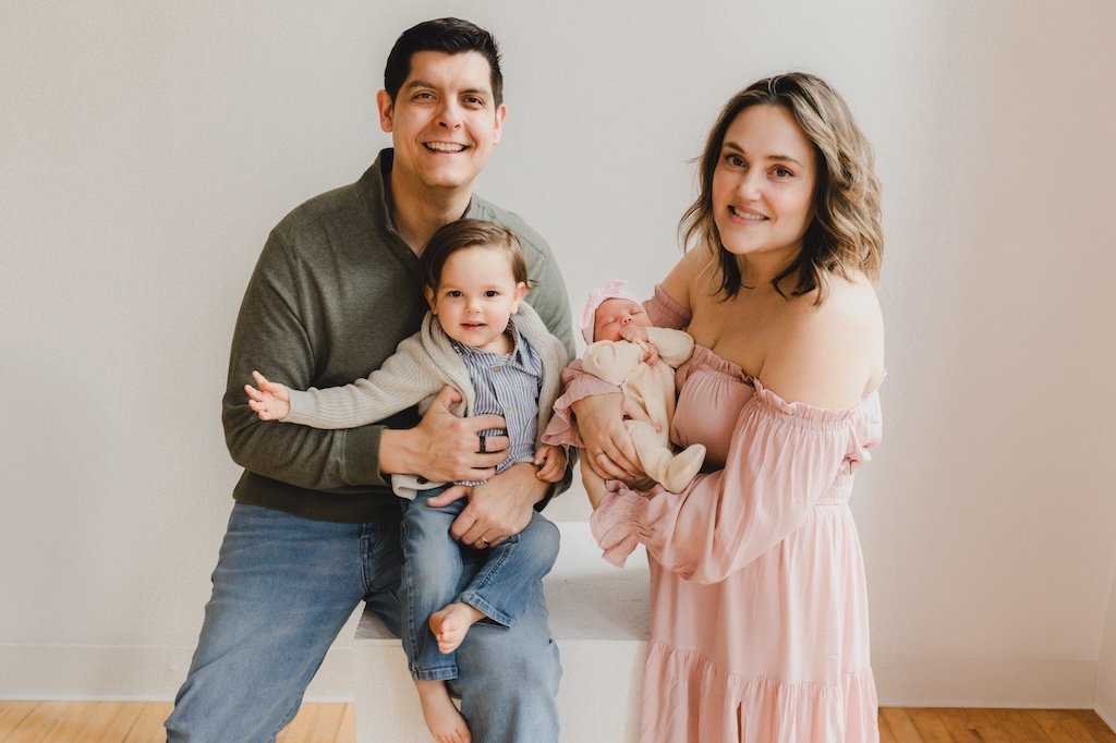 Mom, dad, big brother with newborn sister posing for a picture.