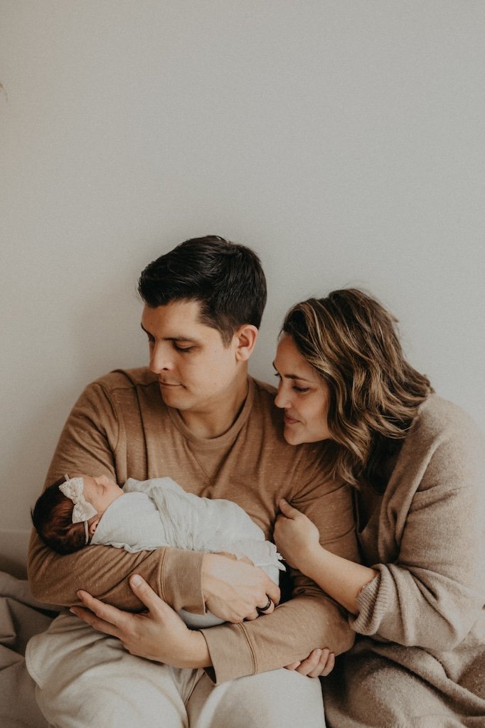 Parents of newborn girl embracing. 