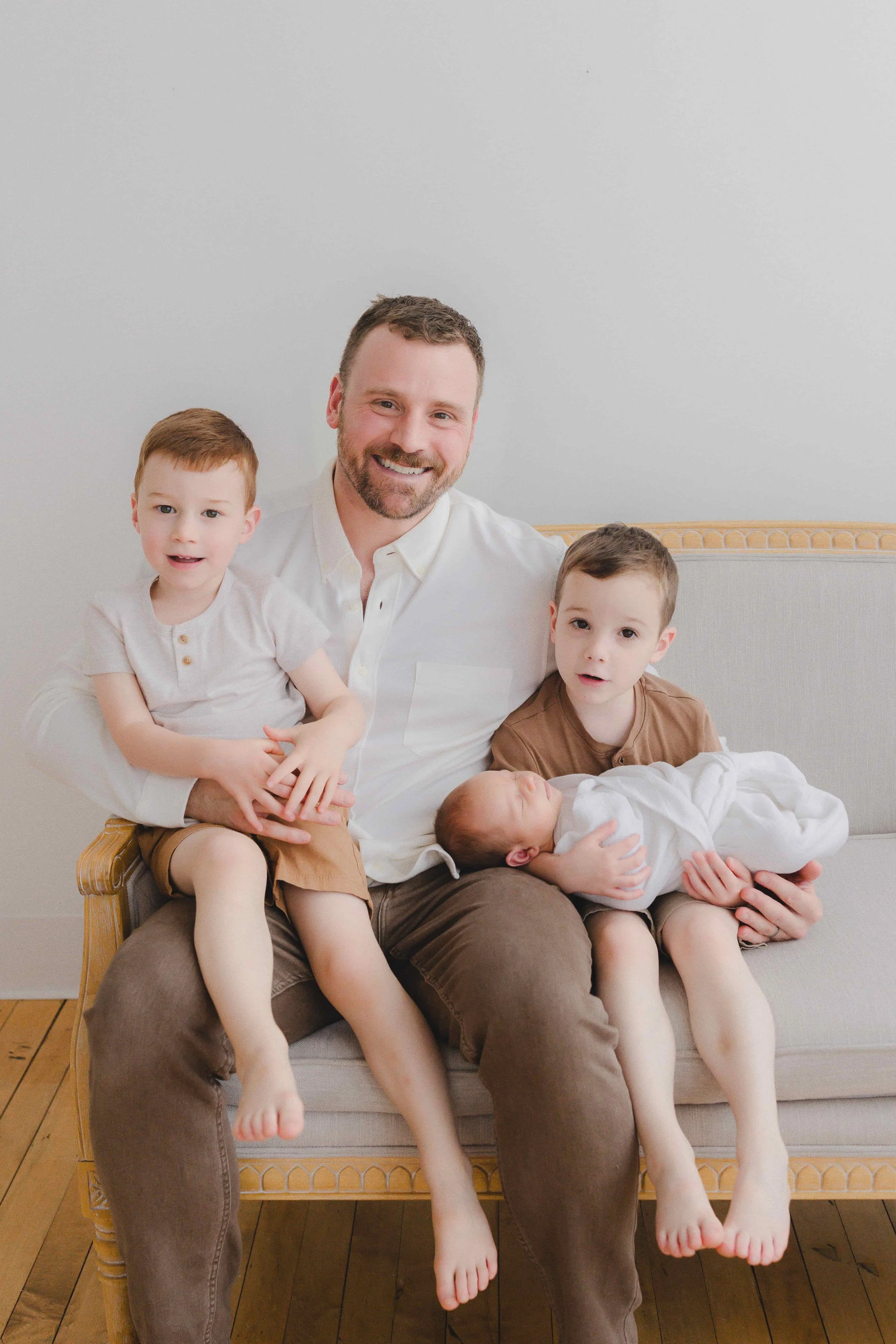 Studio Newborn Photographer Cleveland | Dad with Newborn and Sons on Couch