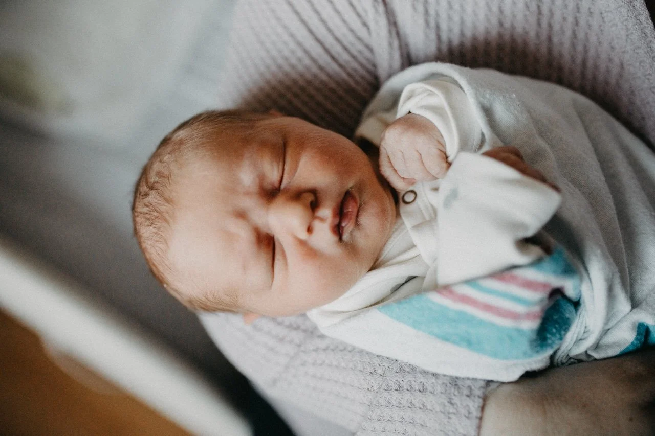 Fresh 48 newborn photo showing a parent gently holding baby in a bright hospital room