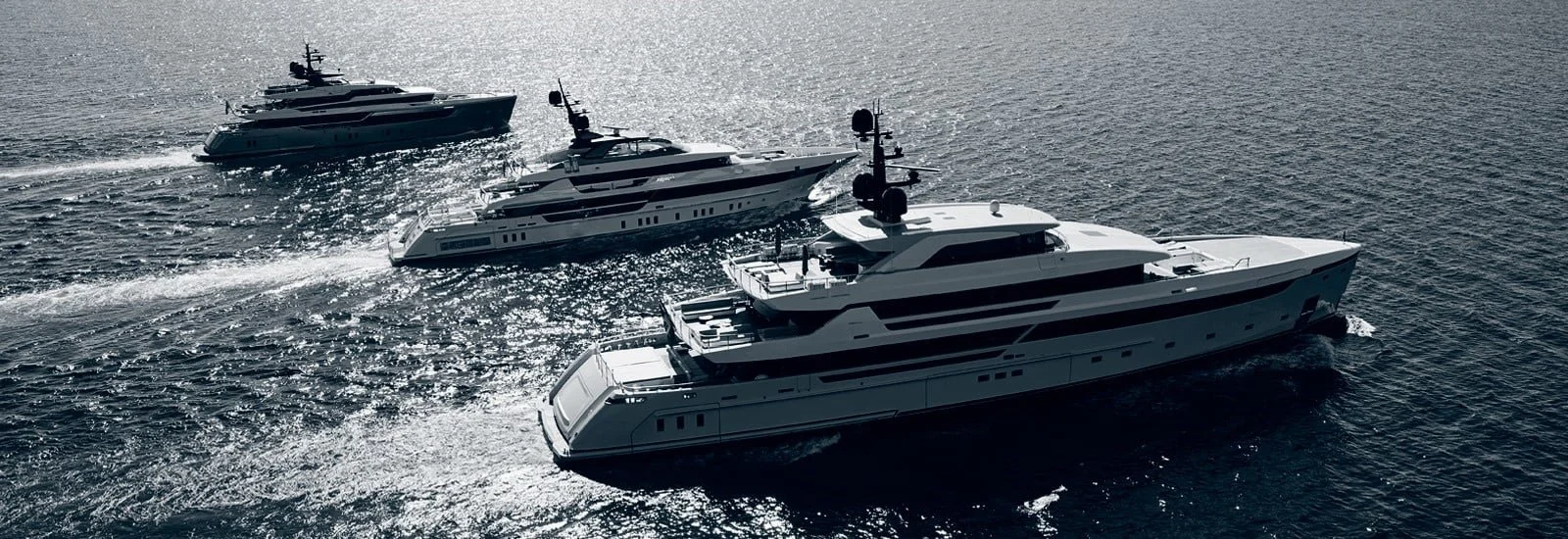 Global Wealth Office featuresfour large luxury yachts sailing on the ocean, leaving white foam trails behind.