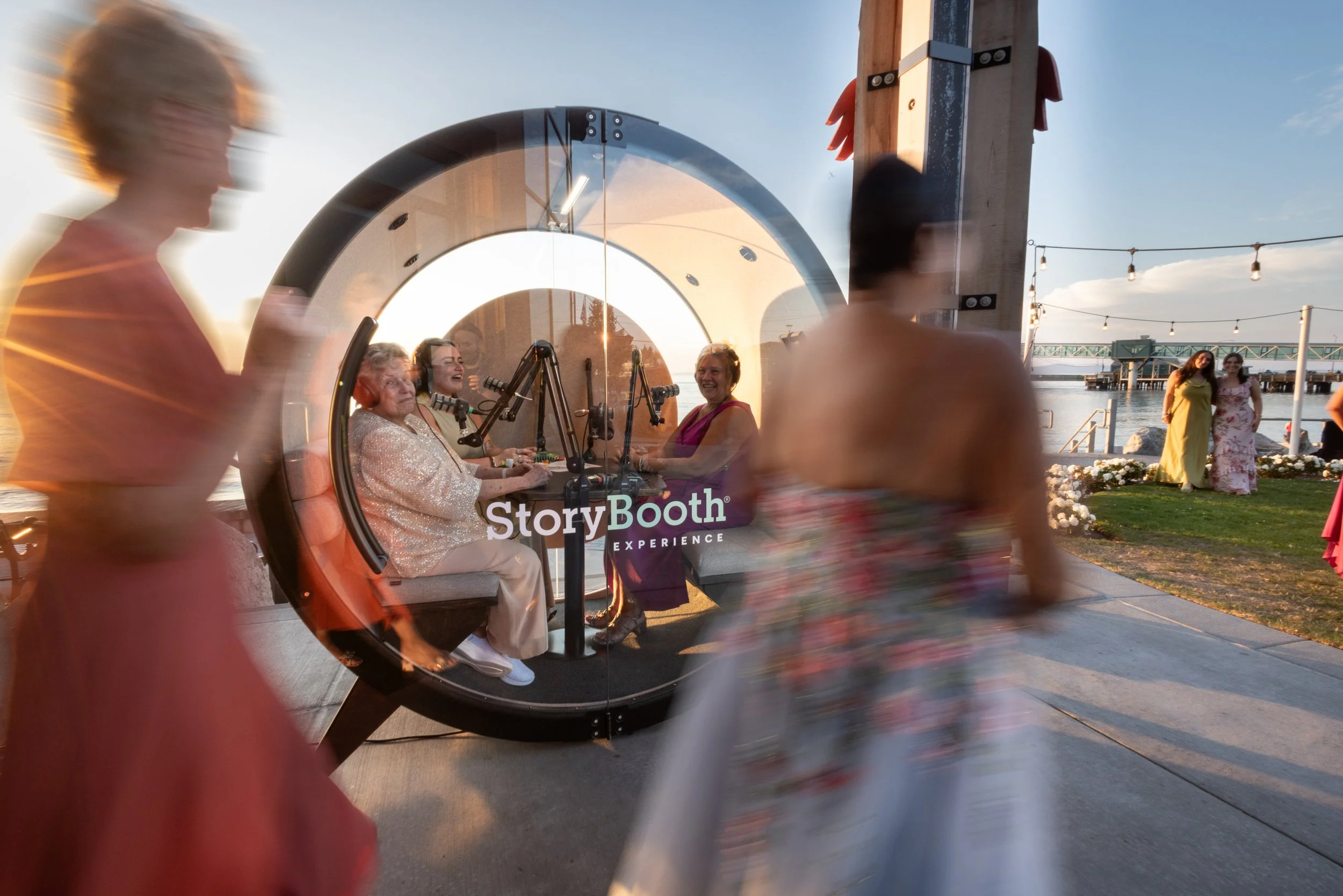 Wedding guests walking by the podcast booth full of people. Story Booth Experience product photography at a wedding in Seattle.