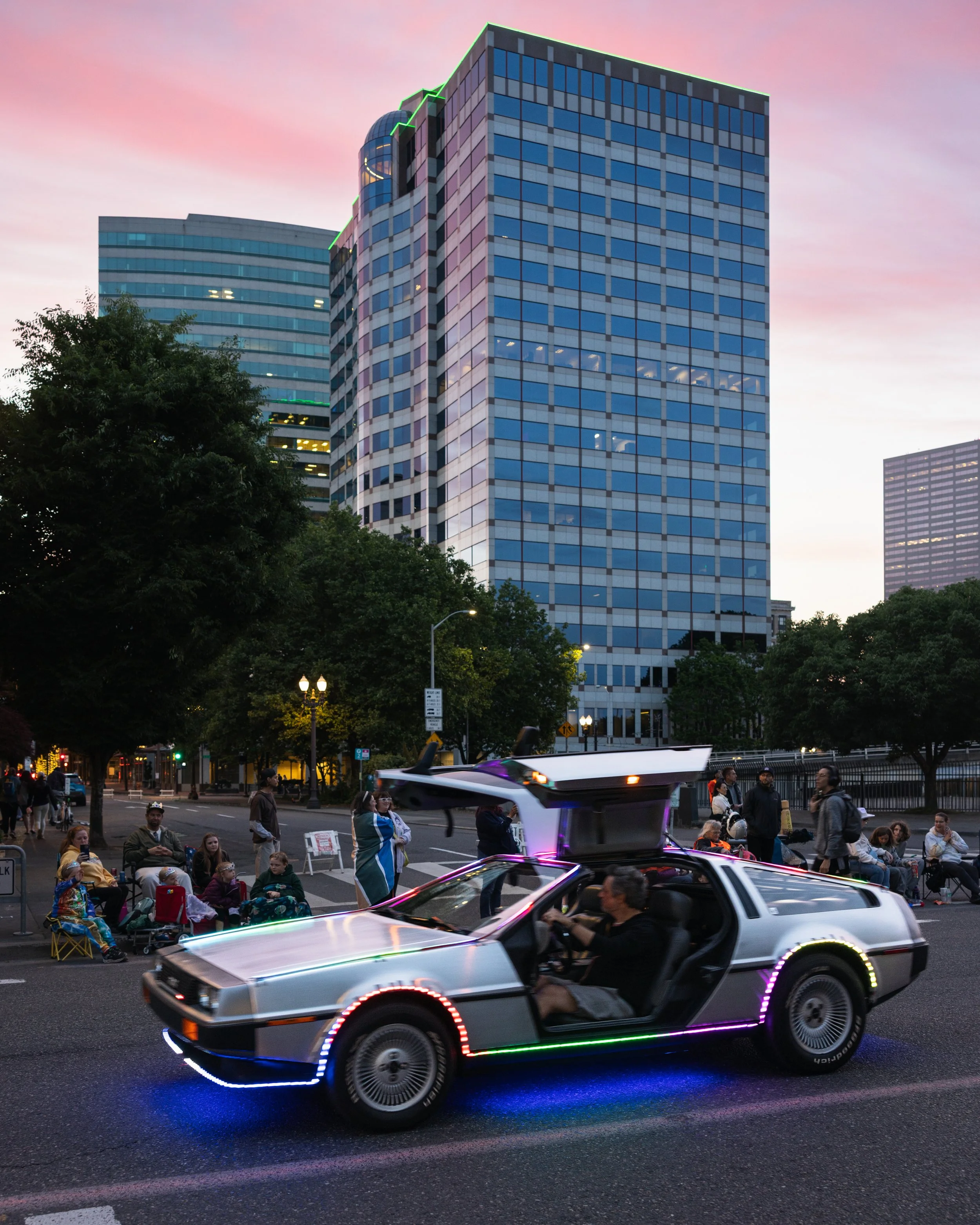 A Delorean drives with it's doors open and the city in the background in the Starlight Parade in Portland, OR.