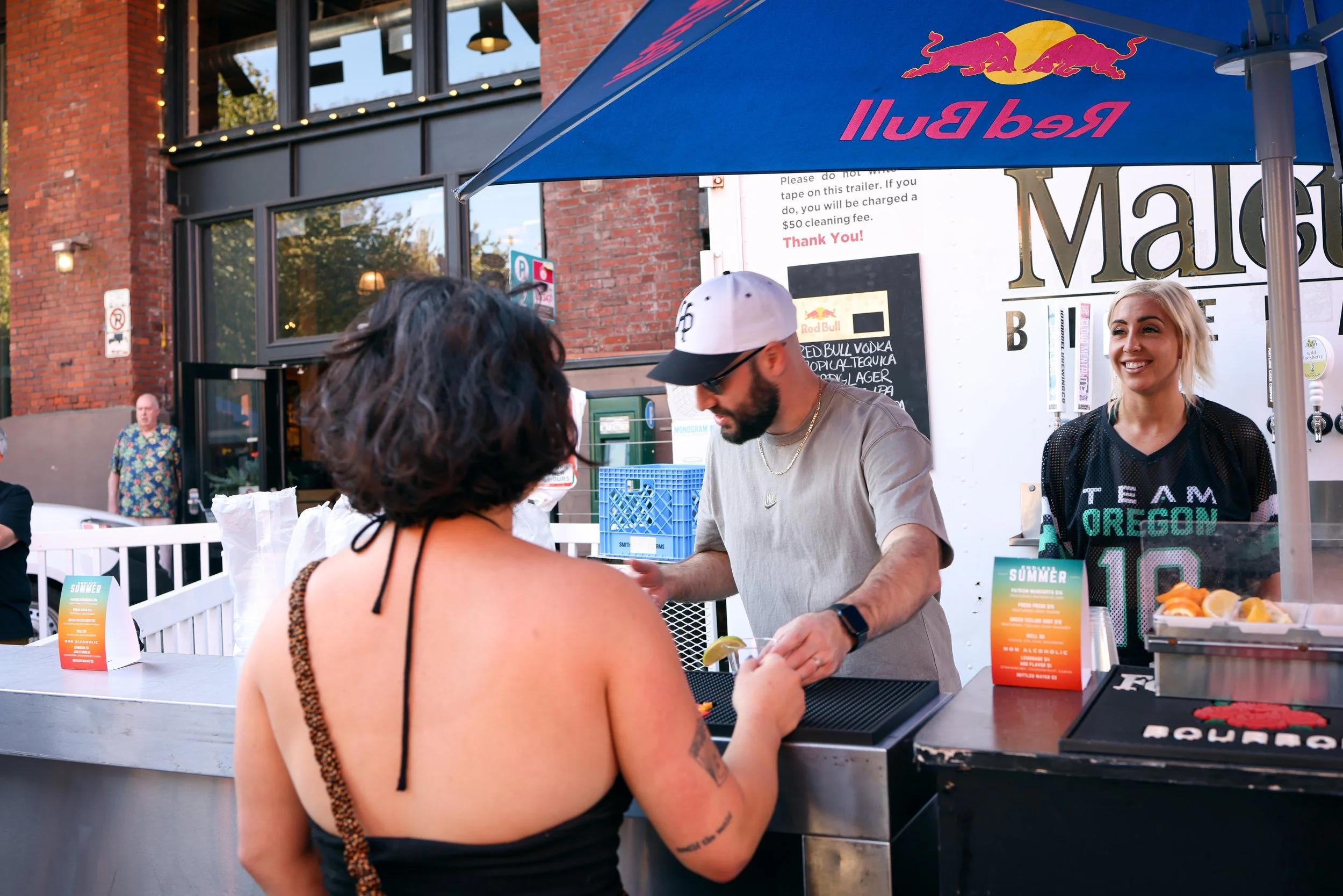 A bartender serving a guest under a Red Bull unbrella at the Pearl Summer Party in downtown Portland, OR.