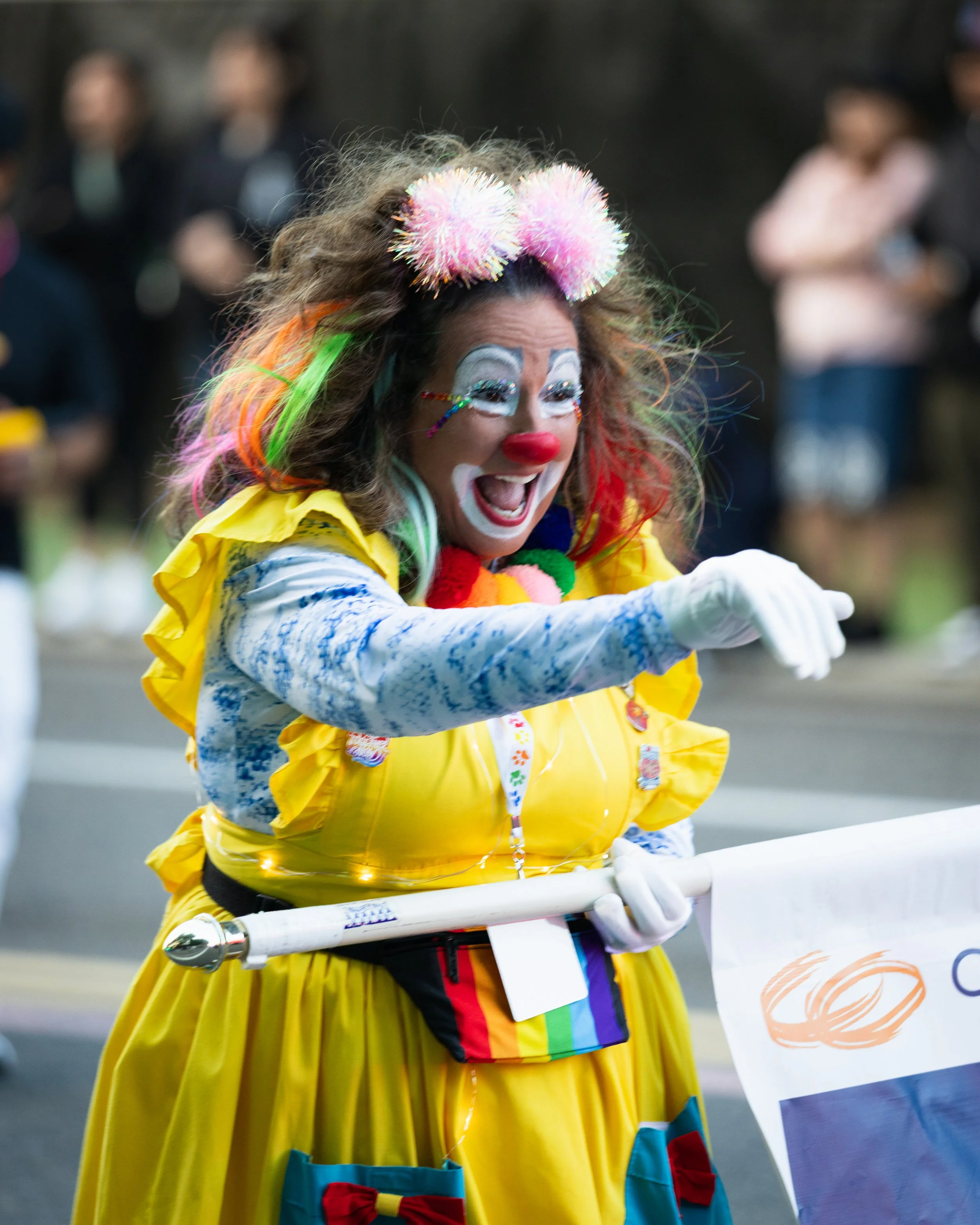 A clown waving to people and smiling in the Starlight Parade in Portland, OR.