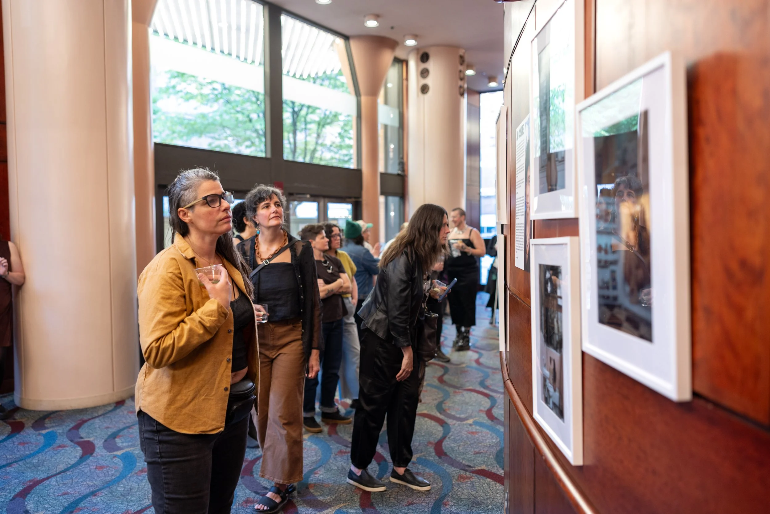 People looking at exhibition at Framing Our Presence event at Portland 5 Winningstad Theater in Portland, Oregon. Event Photography bu JP Bogan.