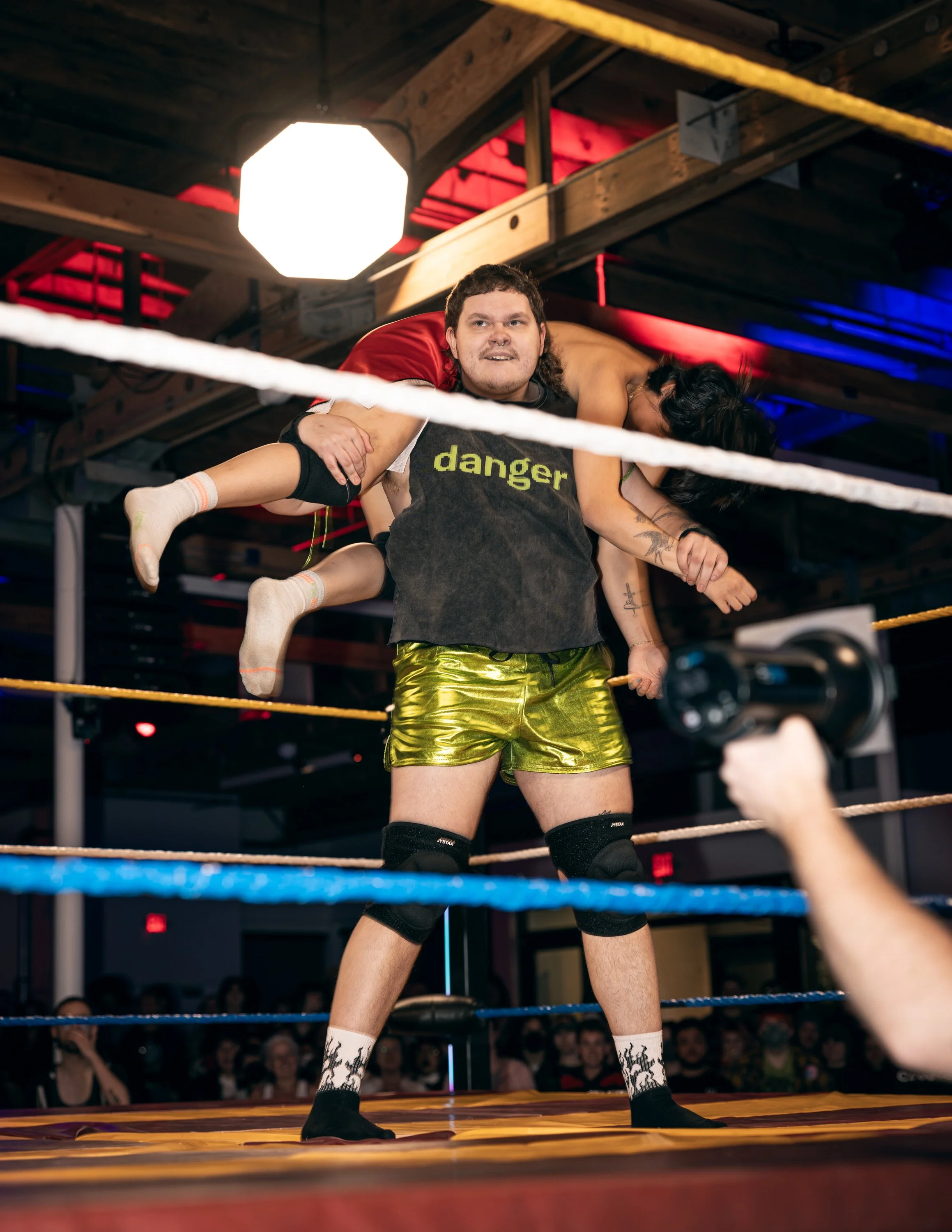 A trans wrestler lifting their opponent over their head at TBOY Wrestling in Portland, OR.