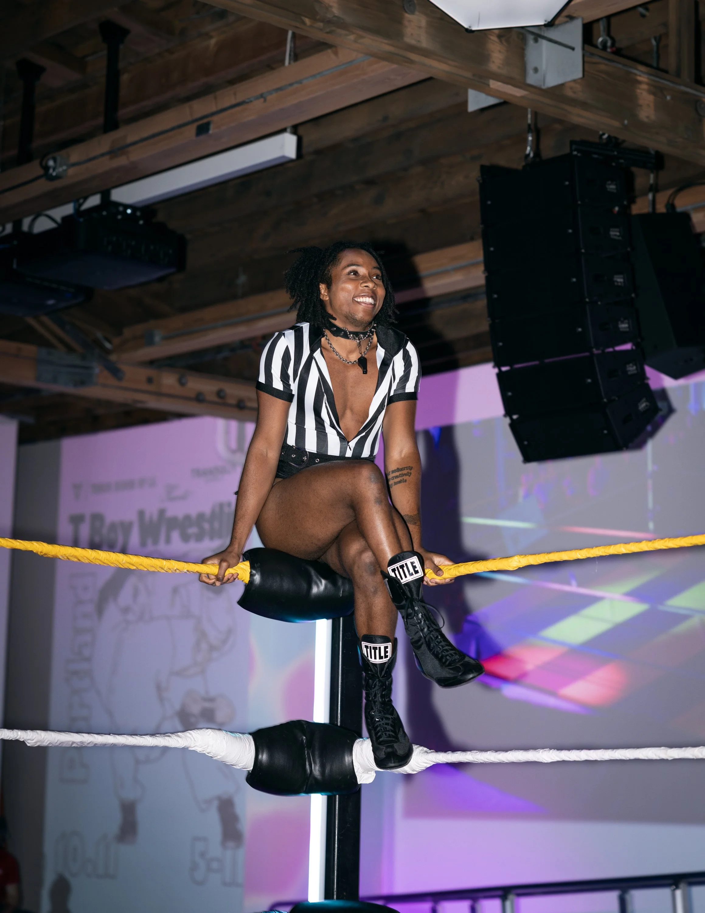 A referee smiling in the ring at TBOY Wrestling in Portland, OR.