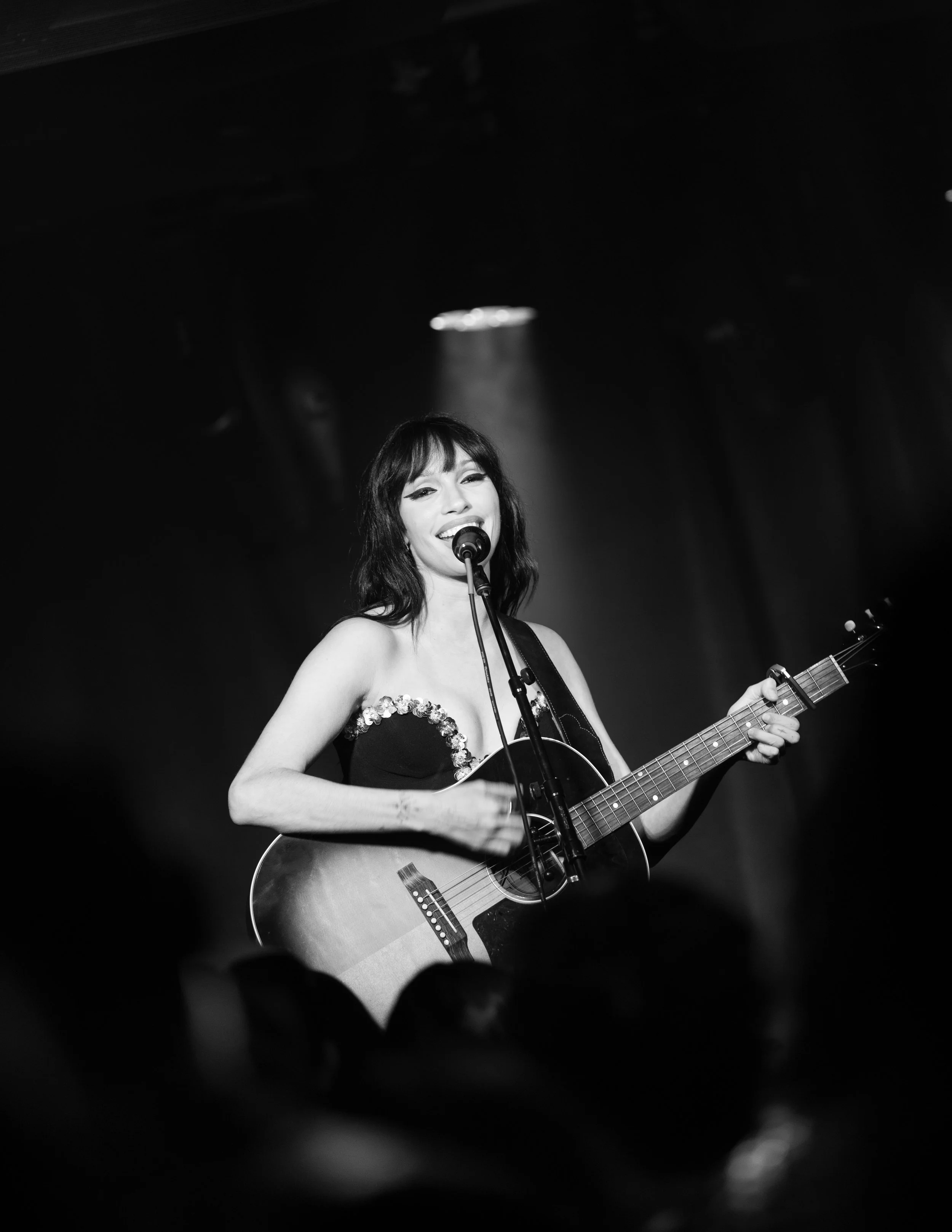 Black and white concert photography of Syd Taylor playing acoustic guitar at her performance at The Get Down music venue in Portland, OR. 