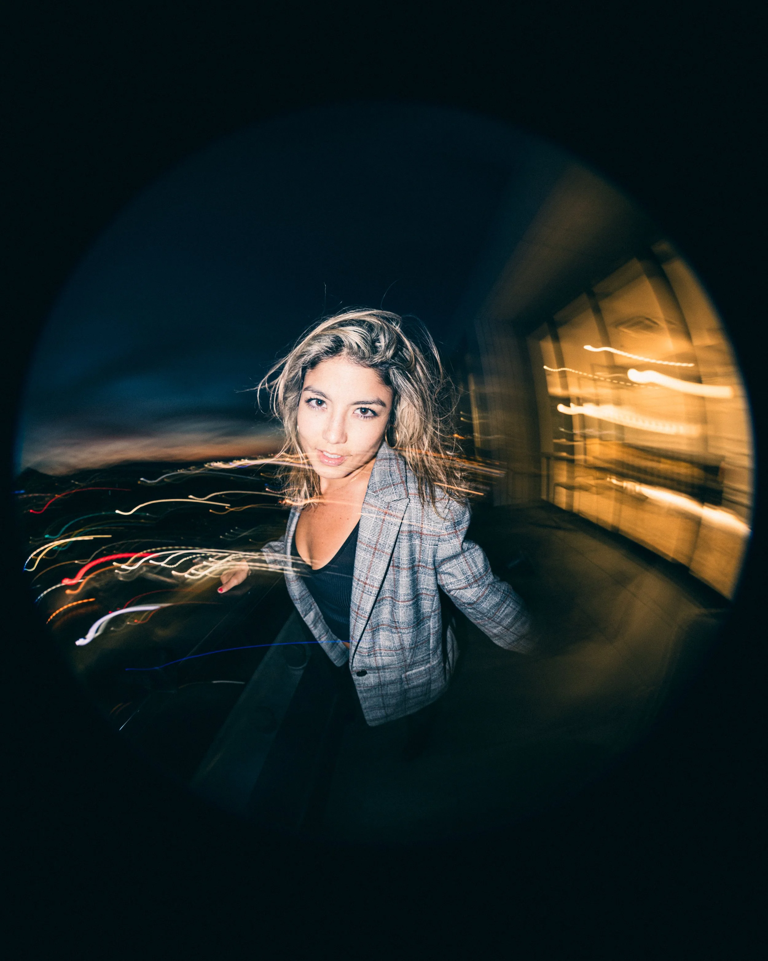 Model, Kim Gonzalez, on a PDX rooftop at sunset posing with a Calvin Klein jacket and long exposure. Portland fashion photography by JP Bogan. Photo taken with with a Venus Optics Laowa 8-15mm f/2.8 Fisheye Lens and a Canon R5.