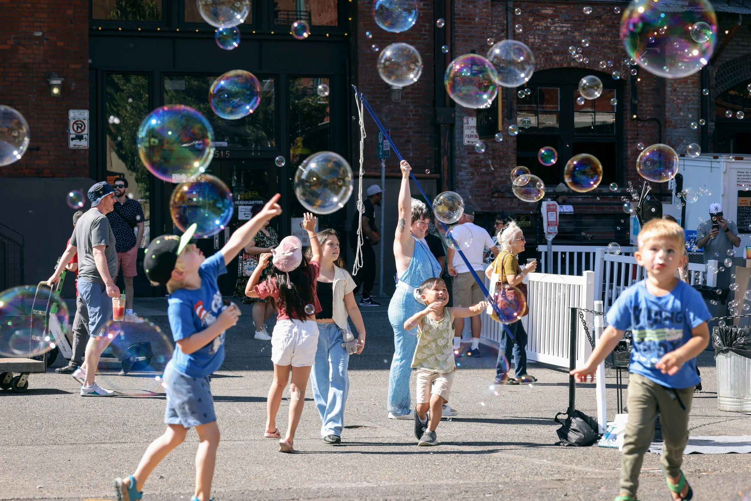 Children playing and chasing balloons at the Pearl Summer Party in downtown Portland, OR.