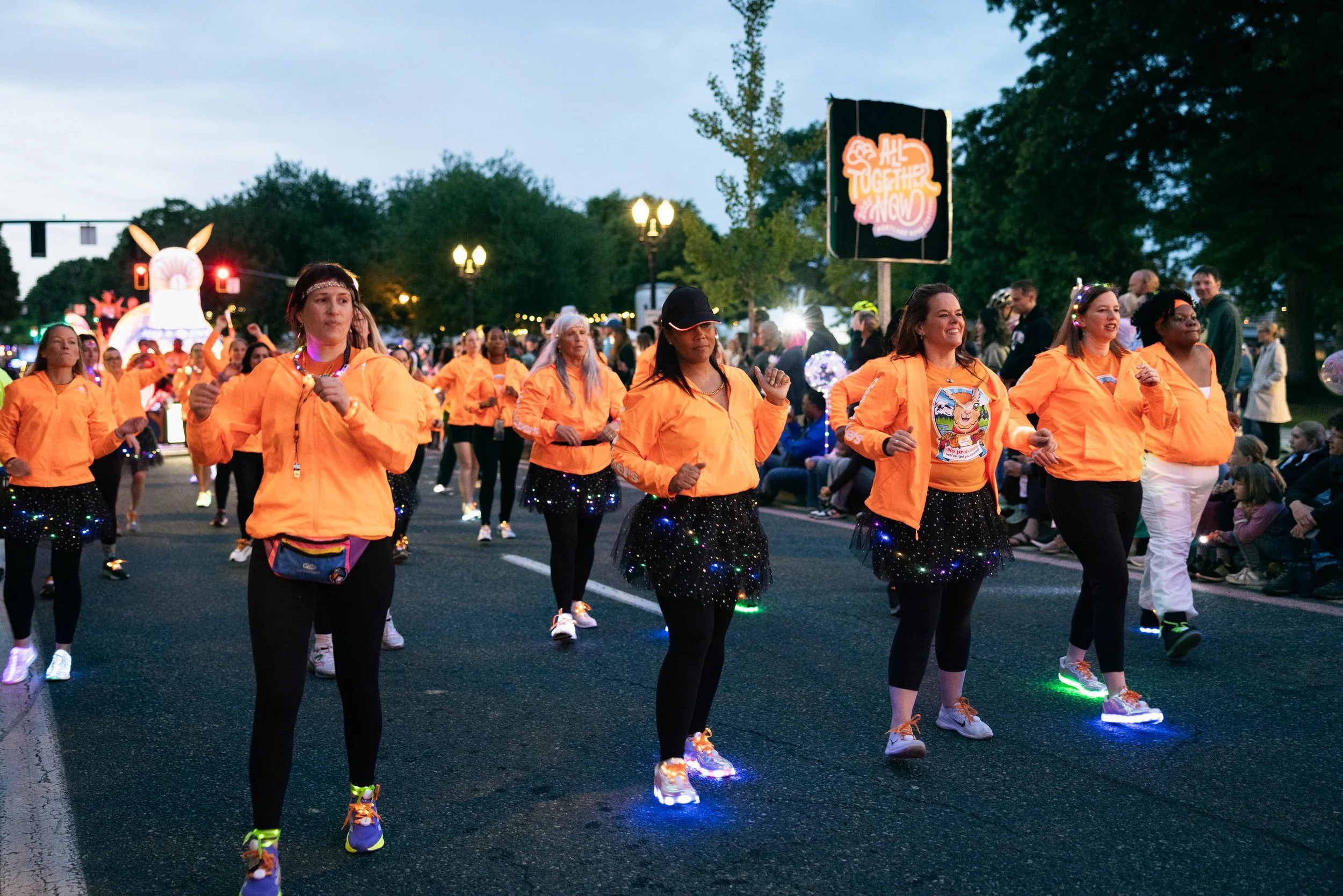 Women wearing bright orange dancing in the Starlight Parade in Portland, OR.